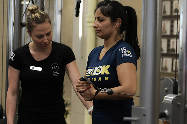 FFC Personal Trainer assisting FFC West Loop member in cable cord workout.